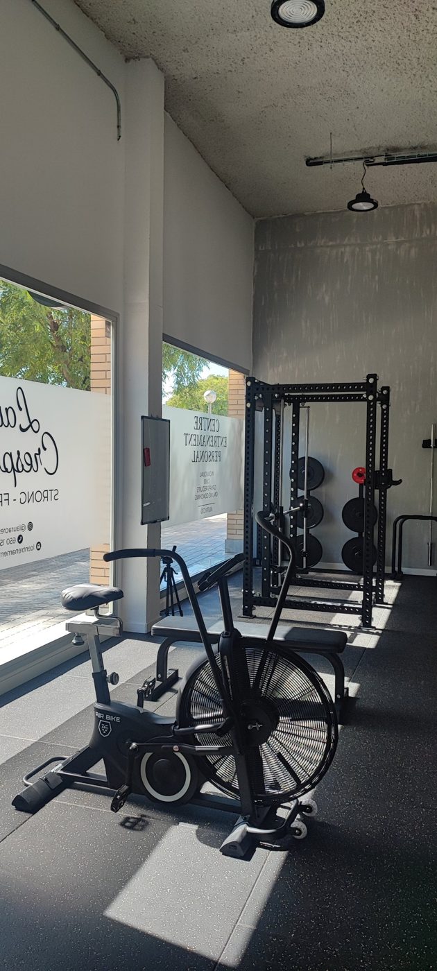 Zona de fuerza con rack, discos y bicicleta de aire
